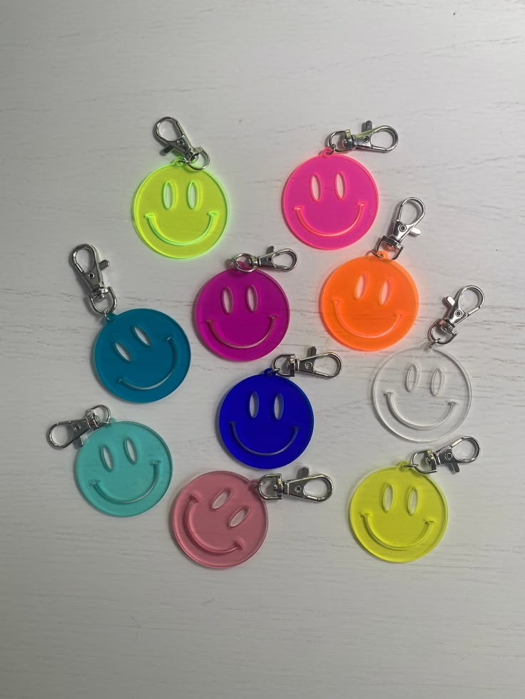 six smiley face keychains with different colors and sizes are shown on a white surface