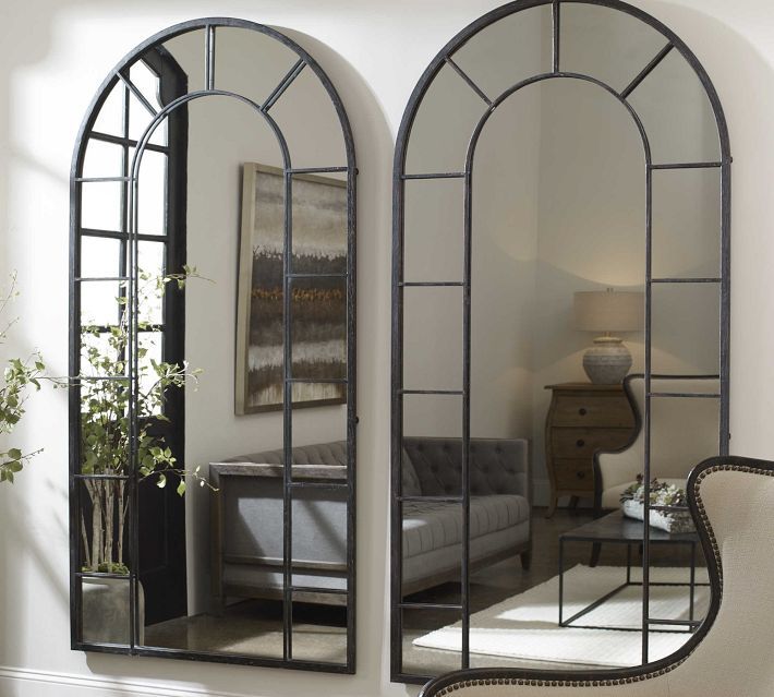 an arched mirror in the corner of a room with a couch and chair next to it