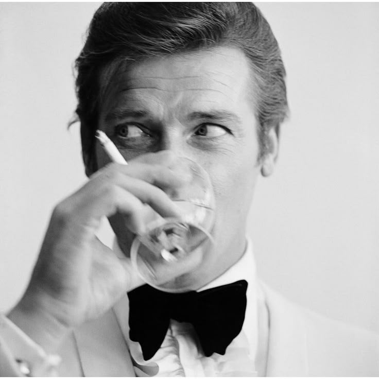 English actor Roger Moore, downs a Martini as James Bond, 17th July 1968. (Photo by Peter Ruck/BIPs/Getty Images)  As an authorized Getty Images Gallery partner, we offer premium quality prints scanned from the original negatives and plates from Getty’s darkroom. All photographic prints are accompanied by a Certificate of Authenticity from Getty Images Gallery.  The B & W resin printing process is a method which is part hand printed and part machine processed on archival paper. An embossed G Roger Moore 007, Shaken Not Stirred, Rudolf Nureyev, Roger Moore, Slim Aarons, Barbra Streisand, Vogue Covers, Sean Connery, Winston Churchill