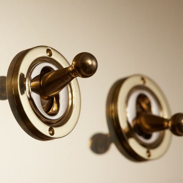 two brass knobs are attached to the wall