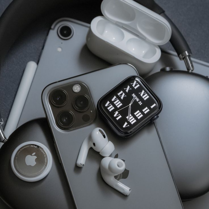 an apple watch, ear buds and headphones on a table