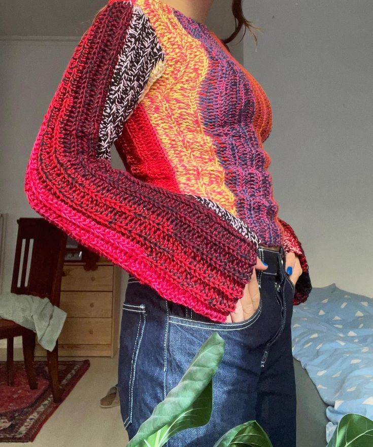 a woman standing in a room with her hands on her hips wearing a colorful sweater