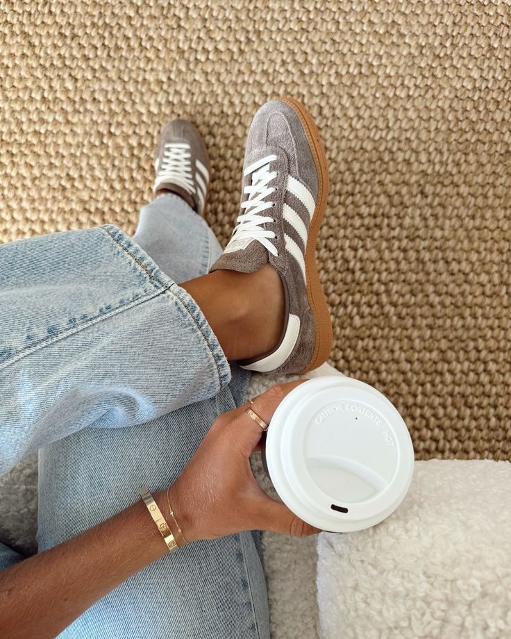 a person sitting on the floor with their feet up and holding a coffee cup in their hand