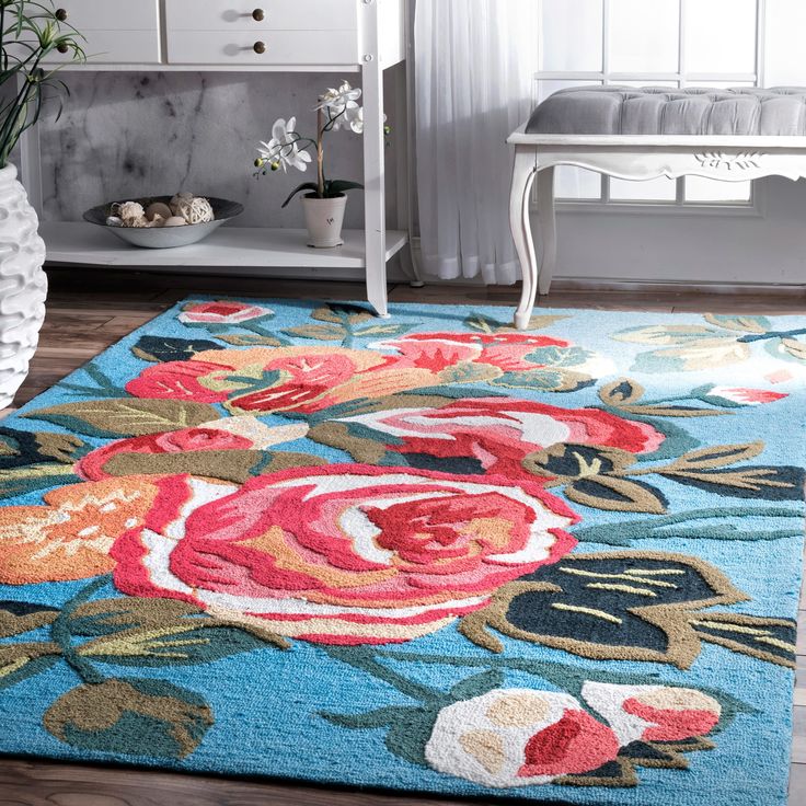 a blue rug with red and pink flowers on it in front of a white dresser