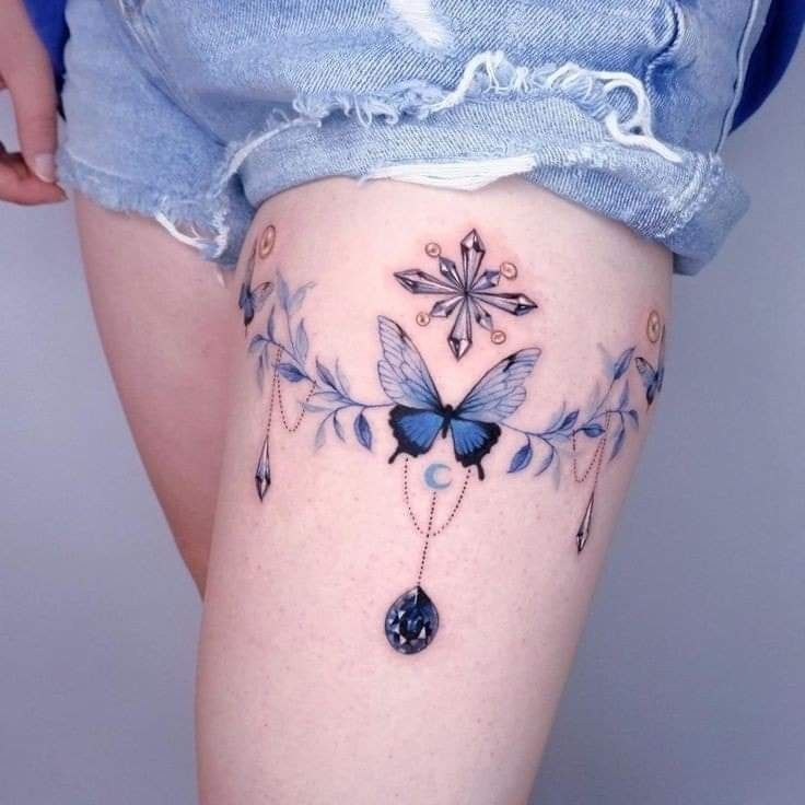 a woman's thigh with blue butterflies and jewels on the bottom part of her leg