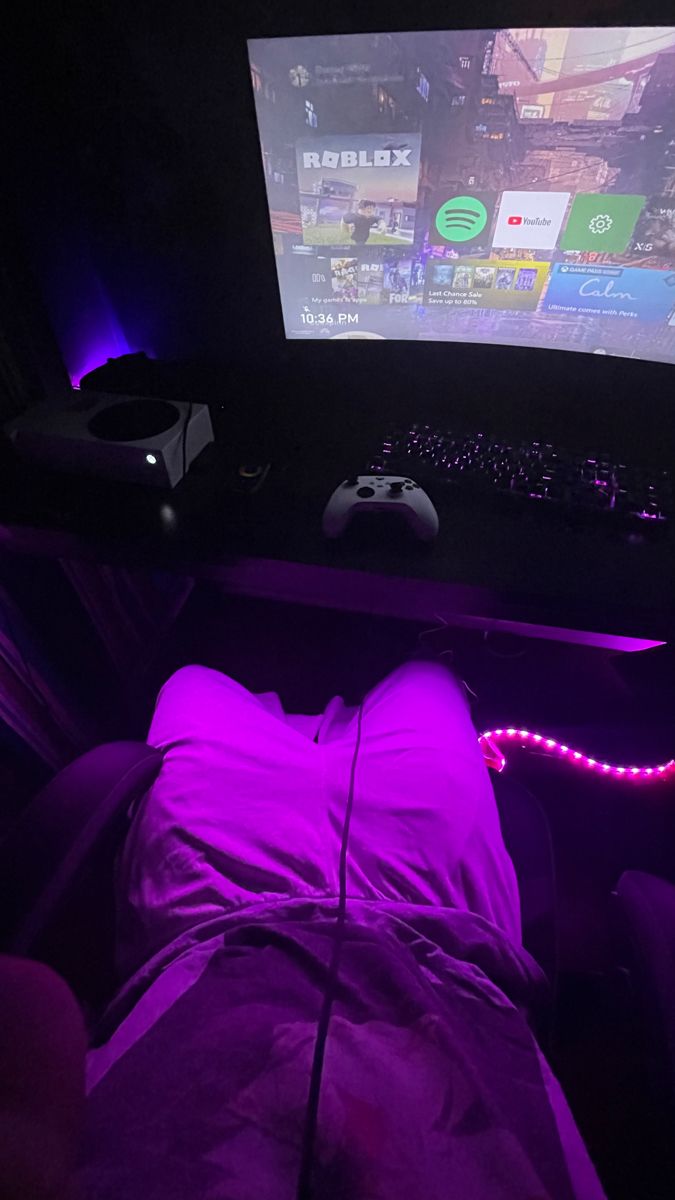 a person is laying down in front of a computer with purple lights on the screen