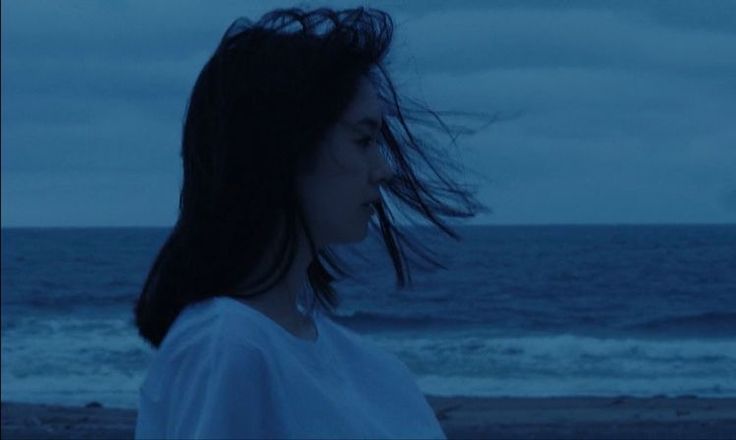 a woman standing on top of a beach next to the ocean