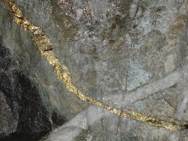 a close up view of some rocks with gold paint on them and water running down the side