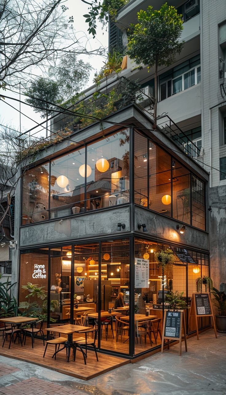 an outdoor restaurant with tables and chairs in front of the building at dusk, surrounded by tall buildings