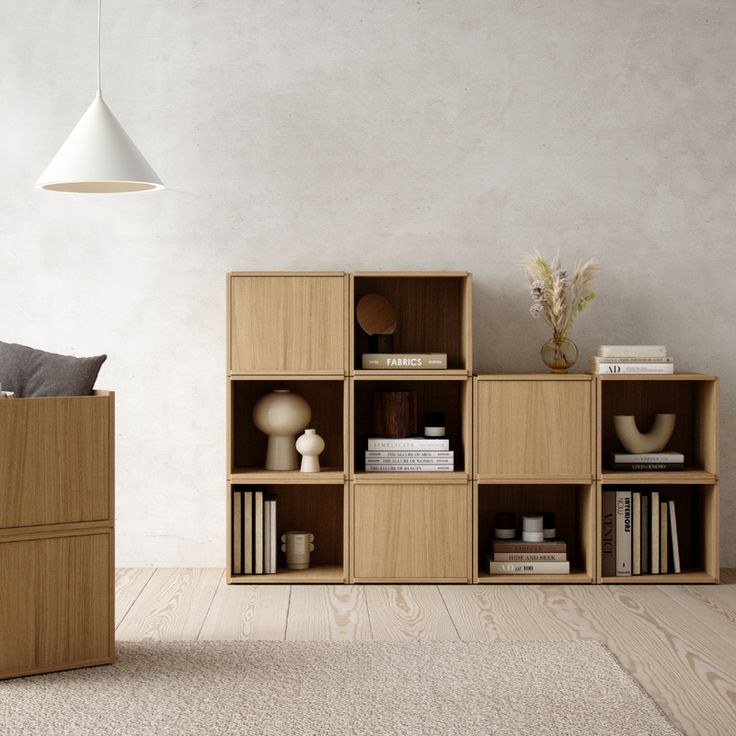 a wooden shelf with books and vases on it next to a wall mounted lamp