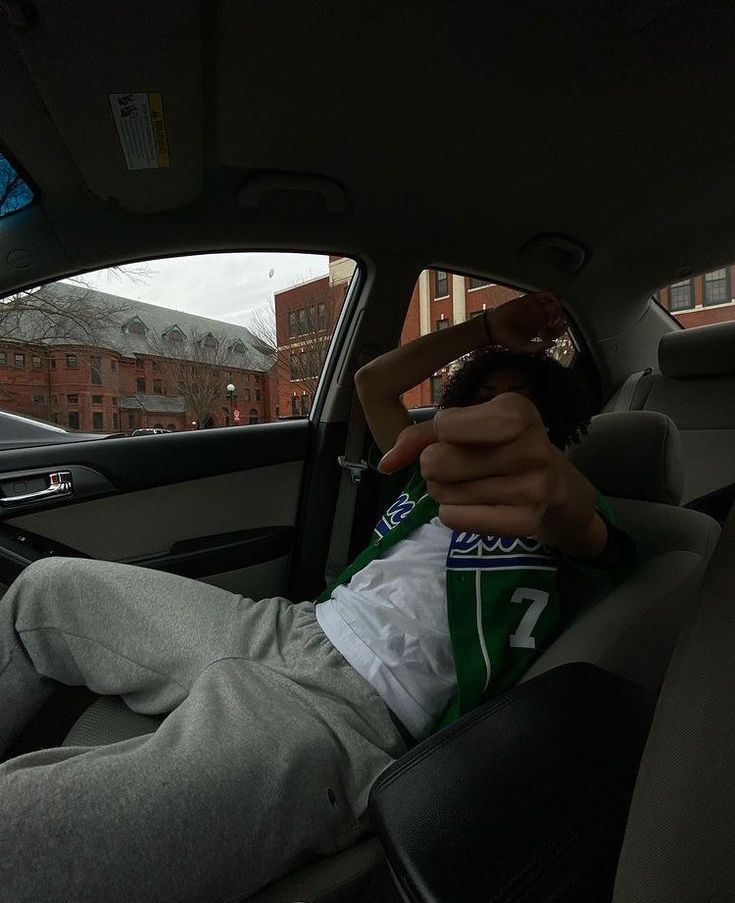 a man sitting in the back seat of a car with his hand on his head