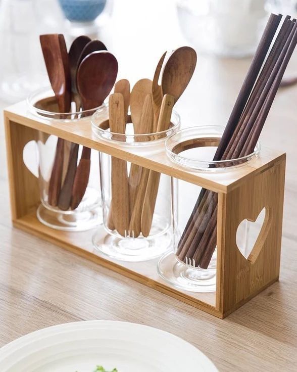 wooden utensils and spoons in glass containers on a table with white plates