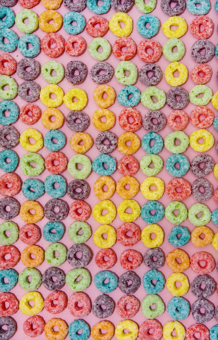 there are many different colored donuts on the pink surface with sprinkles