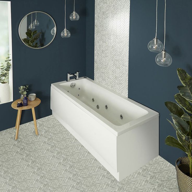 a large white bath tub sitting next to a plant in a room with blue walls