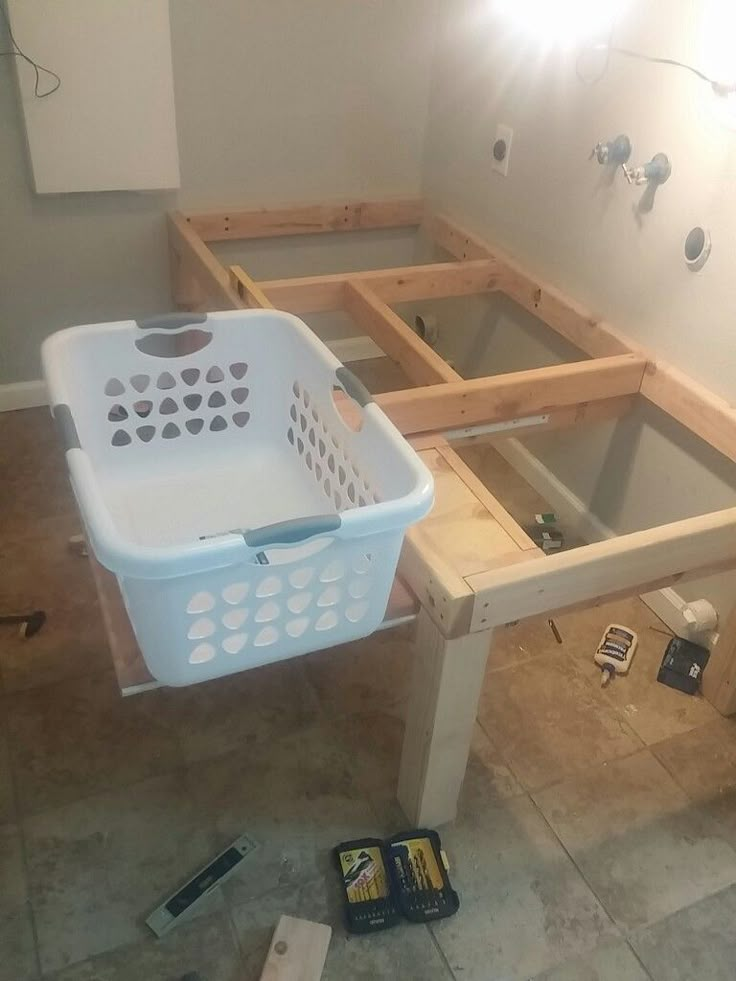 a white basket sitting on top of a wooden table next to a sink in a bathroom