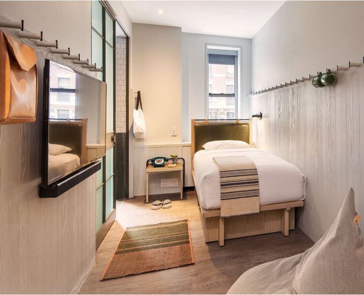 a bed room with a neatly made bed and a flat screen tv on the wall