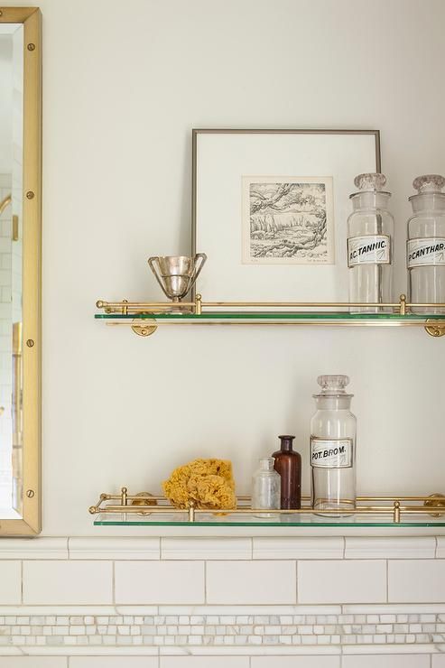 two shelves with jars and other items on them in a white room next to a mirror