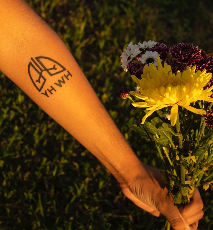 a person holding flowers in their hand with the word hw on it's arm