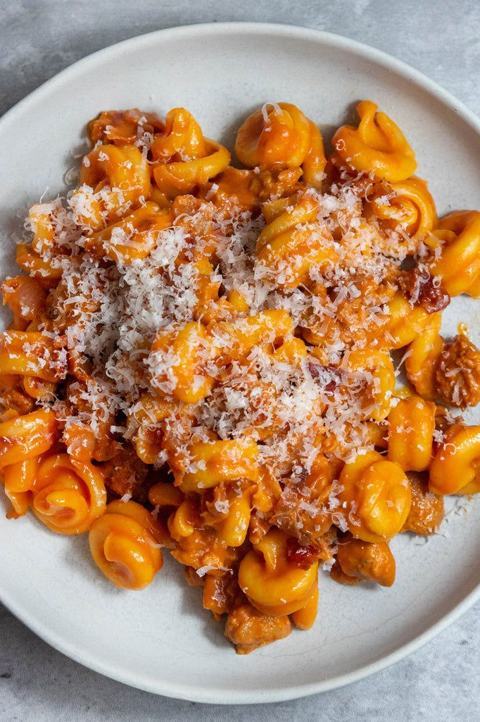 a white plate topped with macaroni and cheese covered in parmesan sauce