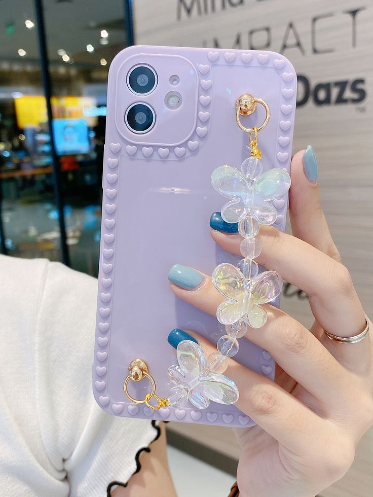 a woman is holding up her phone case with flowers on the front and bottom cover