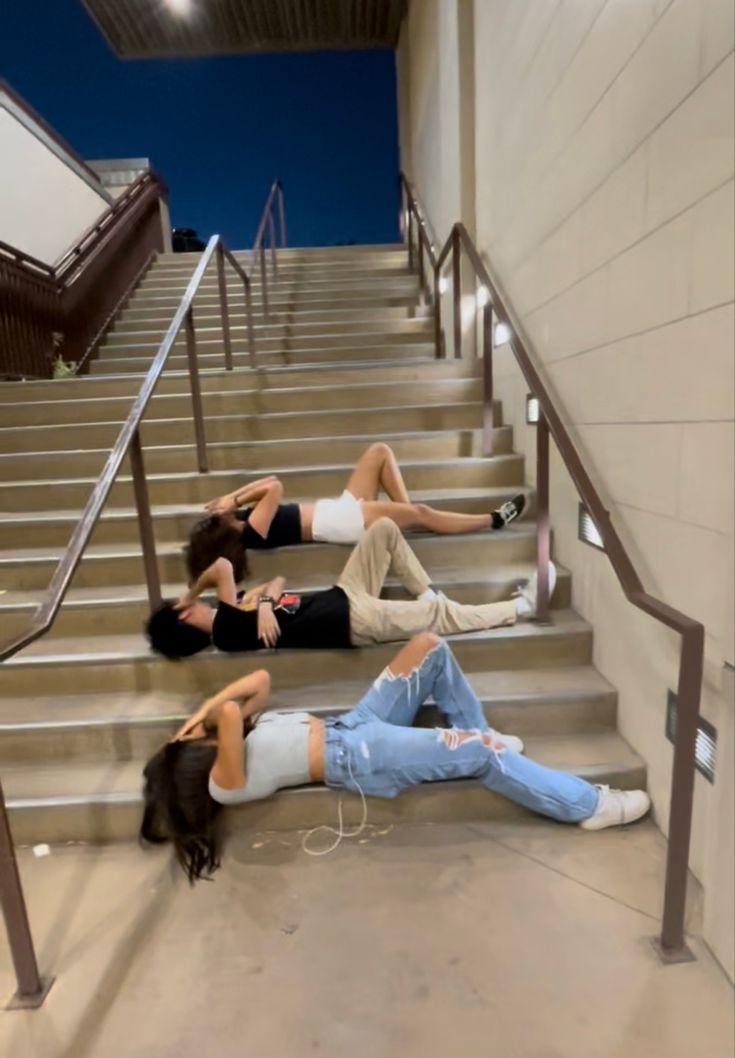 two women laying down on the ground in front of some stairs