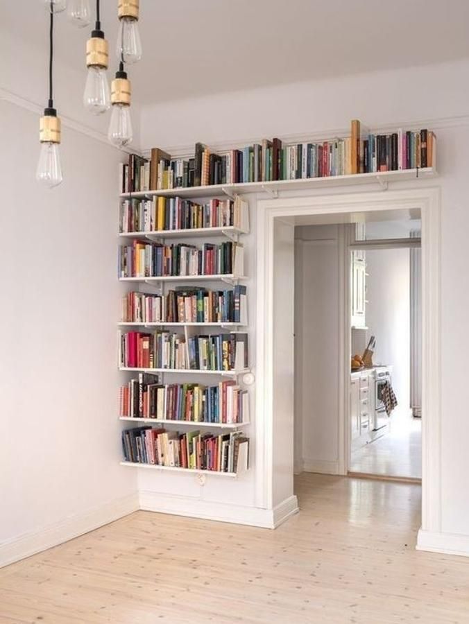 a book shelf filled with lots of books on top of a hard wood floor next to a doorway