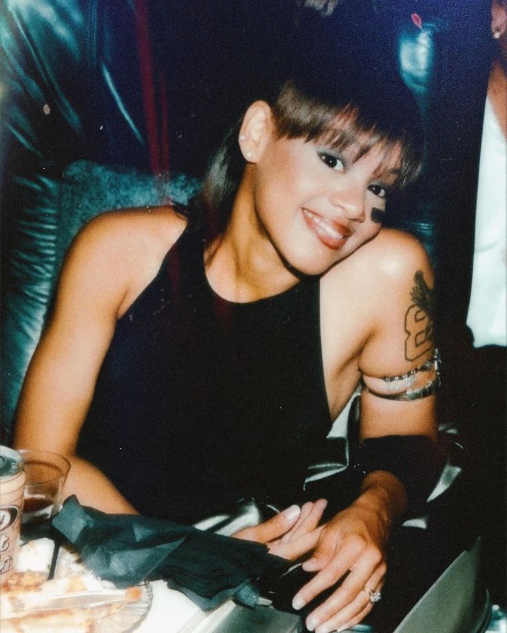 a woman sitting at a table in front of a laptop computer with tattoos on her arm