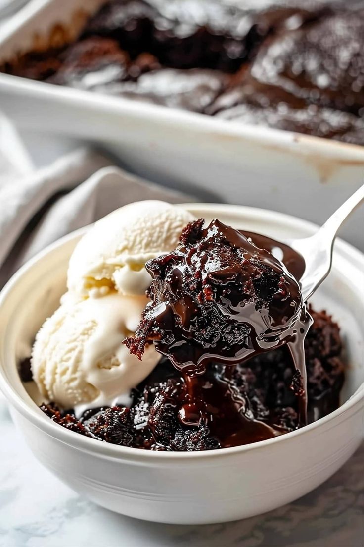 a spoonful of ice cream and chocolate cake in a white bowl on a table