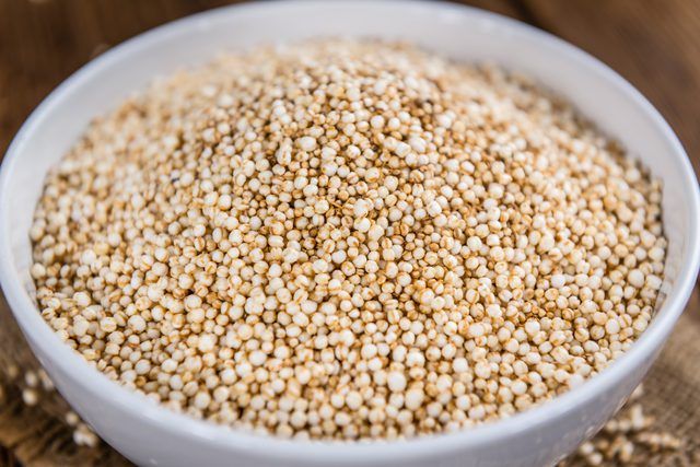 a white bowl filled with sesame seeds on top of a wooden table