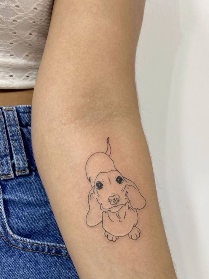 a woman's arm with a small dog tattoo on it