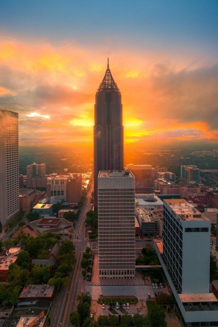 the sun is setting over a city with tall buildings and skyscrapers in the foreground