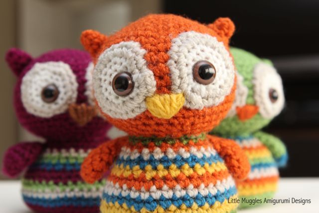 two stuffed animals sitting next to each other on top of a bed covered in crochet