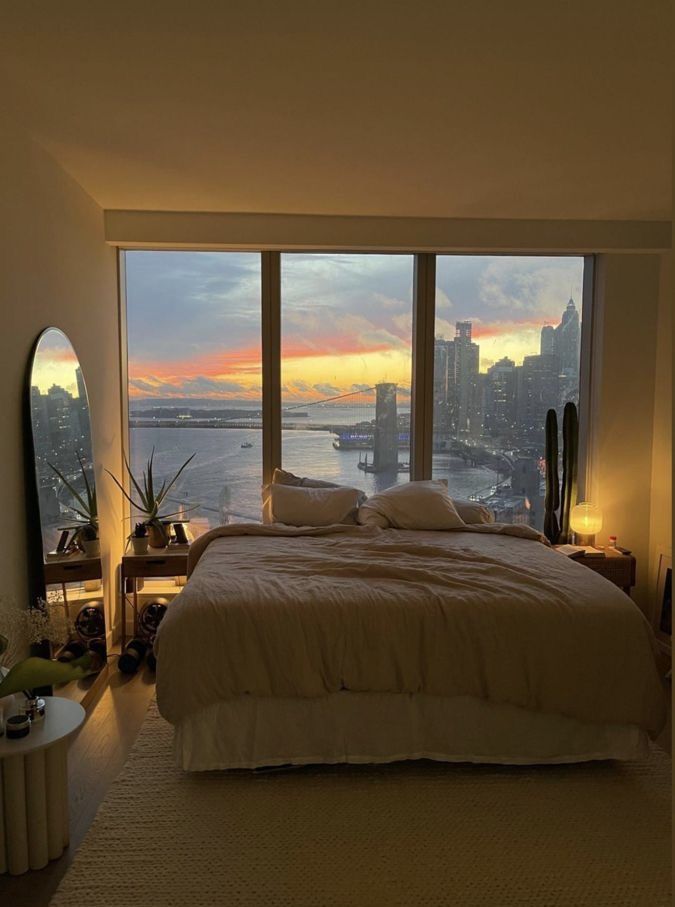 a bedroom with a large window overlooking the water and cityscape in the distance