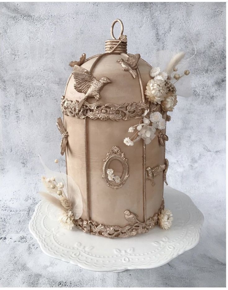 a large cake decorated with flowers and birds on top of a white table cloth covered plate