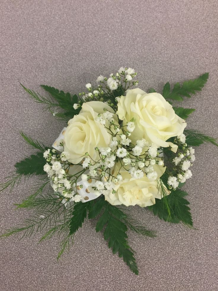 a bouquet of white roses and baby's breath is on the floor with green leaves