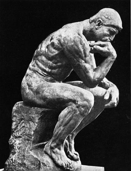 a statue of a man sitting on top of a block of stone with his hands to his face