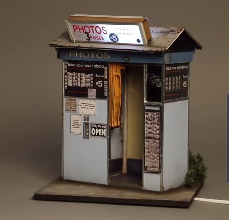 an old fashioned photo shop with signs on the front and side walls, sitting next to a street sign