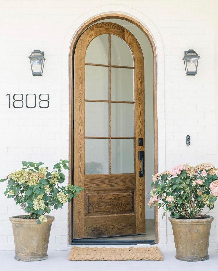 two potted flowers are sitting outside the front door