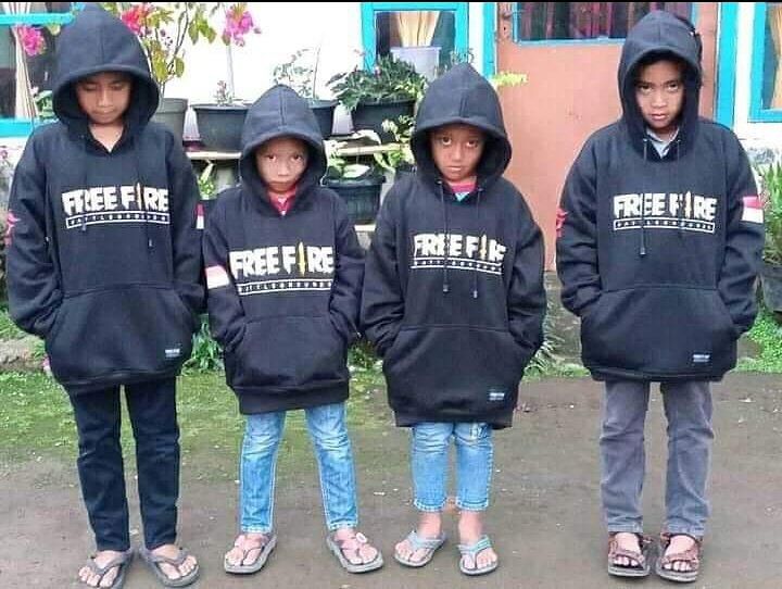 four children wearing black hoodies standing in front of a building