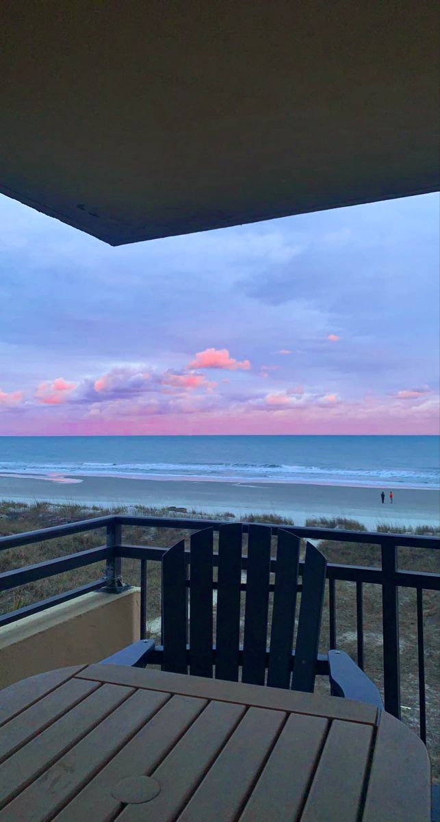 an ocean view from the balcony of a beachfront condo at sunset or dawn with clouds in the sky