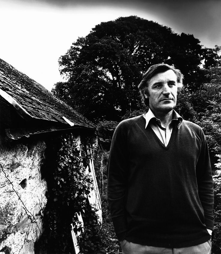 a man standing in front of a building with ivy growing on it's roof