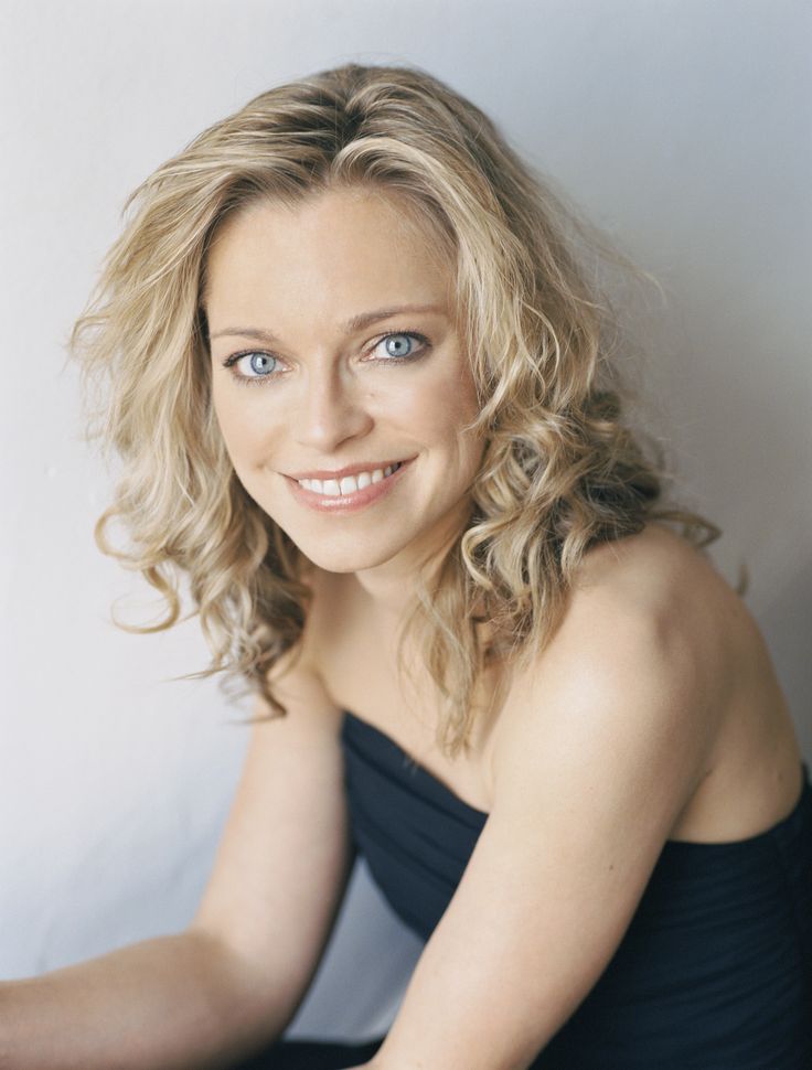 a woman in a black dress posing for a photo with her hands on her knees