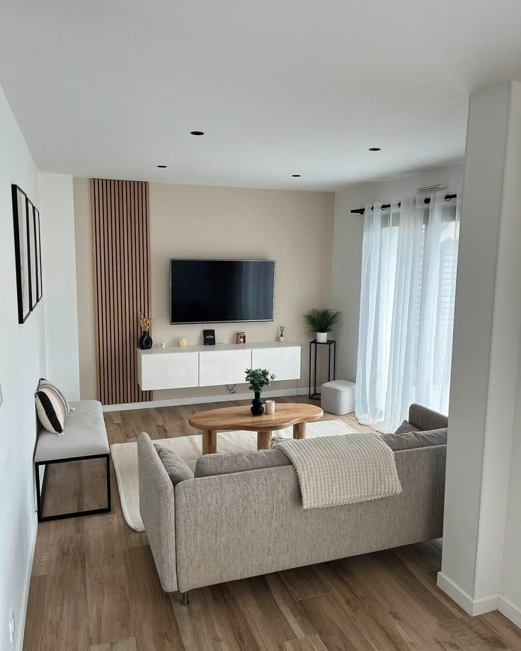 a living room filled with furniture and a flat screen tv mounted on the wall above a wooden coffee table