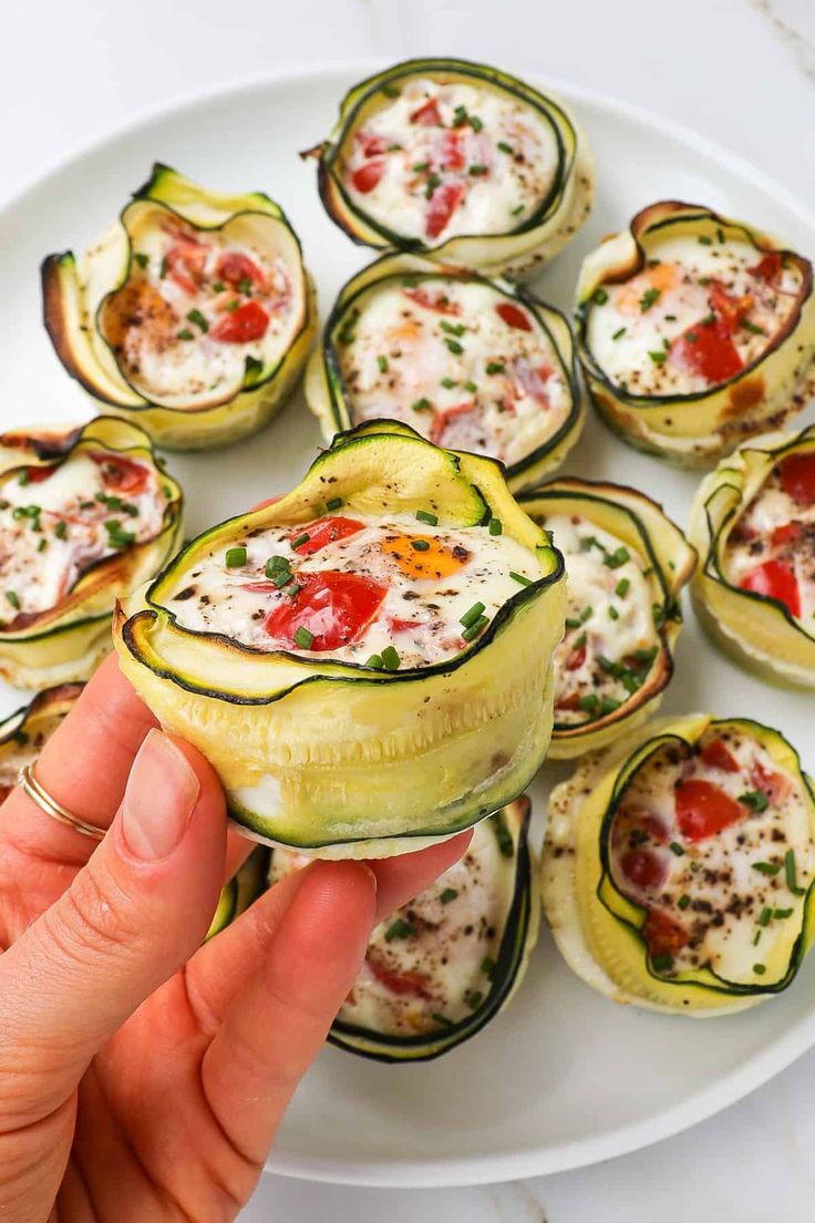 someone is holding up some zucchini cups on a white plate