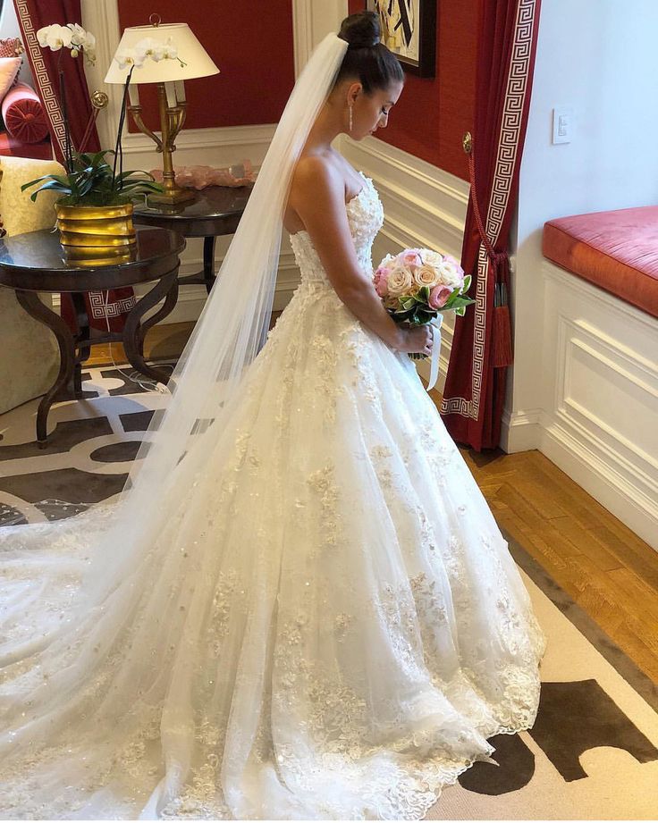 a woman in a wedding dress is looking down at her bouquet