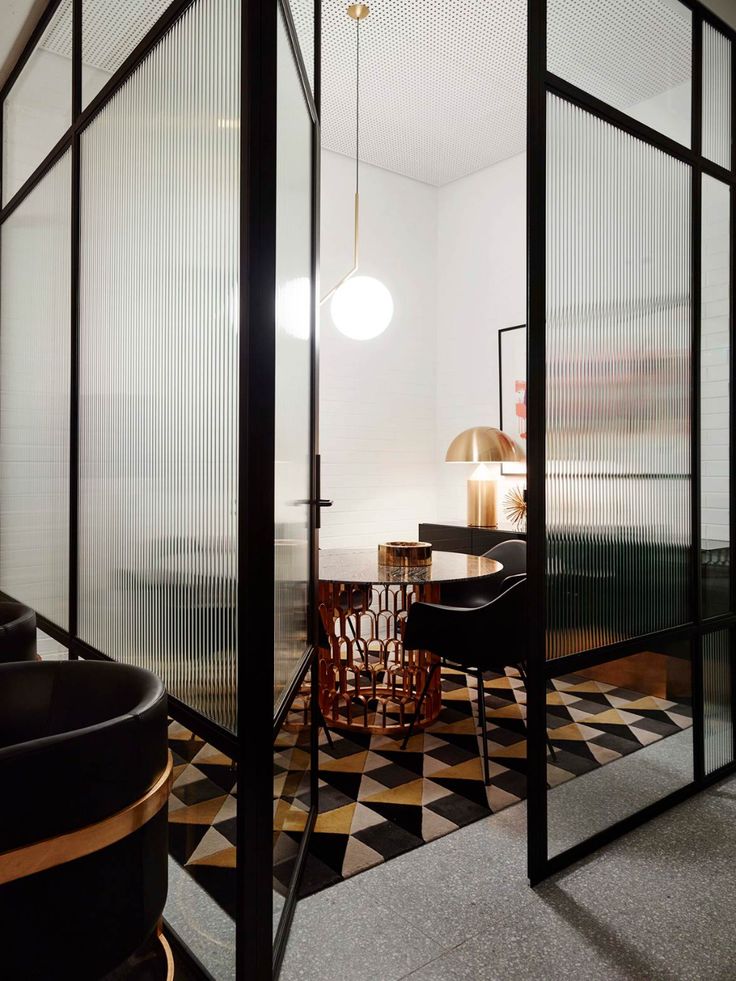 an office with black and white checkered flooring, glass walls, and chairs