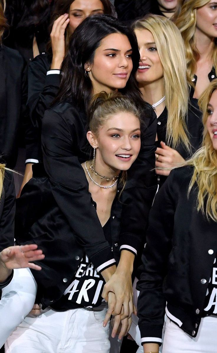 two young women sitting next to each other in front of a group of people at a fashion show