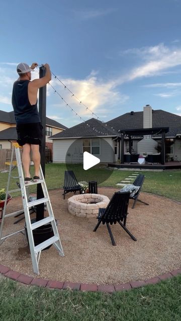 a man standing on top of a ladder next to a fire pit in a backyard