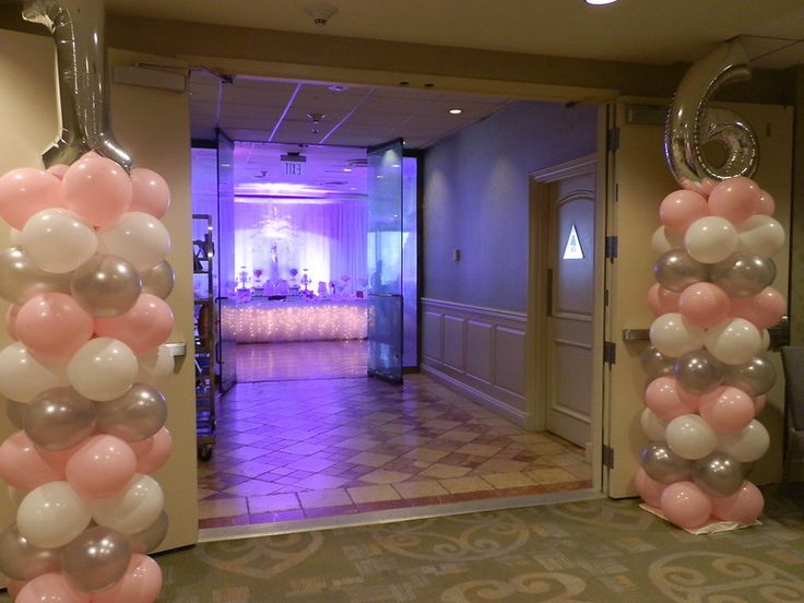 balloons are hanging from the ceiling in front of an entrance to a room with pink and white decor