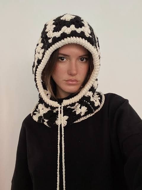 a woman wearing a black and white hoodie with a crochet pattern on it